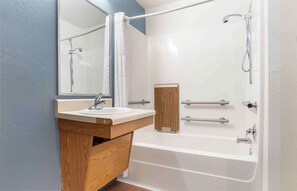 A modern bathroom with a white bathtub, a wooden vanity with a sink, and a large mirror. - Extended Stay America Select Suites - Montgomery (Montgomery)