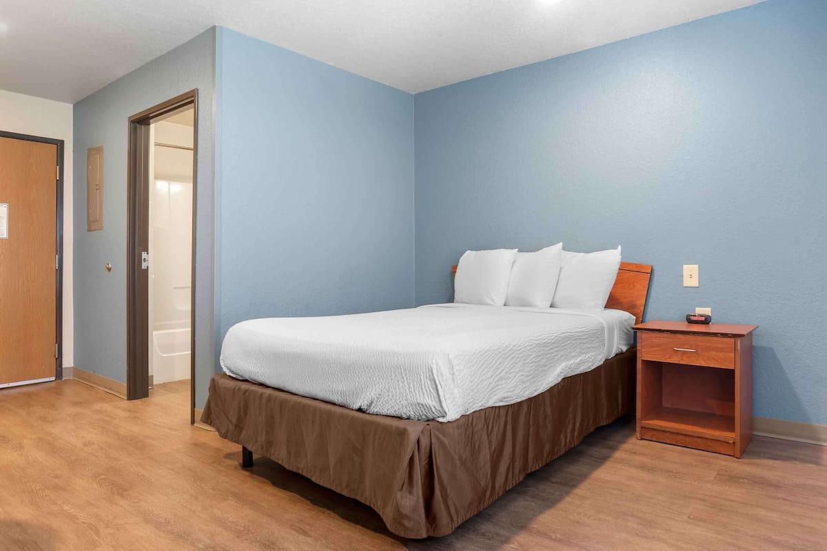 A bedroom with a bed, a nightstand, and a door.