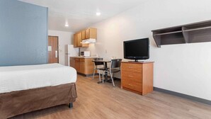A hotel room with a bed, a desk with a chair, a television, and wooden cabinets. - Extended Stay America Select Suites - Montgomery (Montgomery)