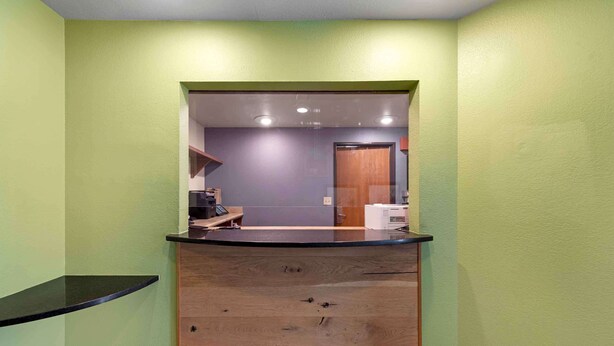 A reception area with a wooden counter, a small desk, and a door leading to another room. - Extended Stay America Select Suites - Montgomery (Montgomery)