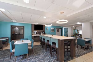 A restaurant with a long counter, blue chairs, and a tiled floor.