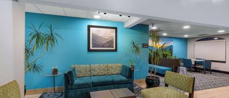 Um hall com parede azul, um sofá, uma mesa de centro e cadeiras.