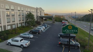 A parking lot with multiple cars and a hotel building in the background.