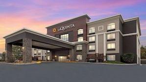 A modern hotel with a stone facade, a covered entrance, and a prominent brand sign.