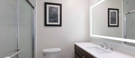 A modern bathroom with a toilet, a sink, and a large mirror.
