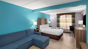 Habitación de hotel con una cama grande, un sofá, un escritorio y un televisor.