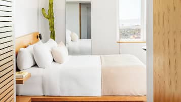 Un dormitorio moderno con cabecera de madera, un espejo grande, un cactus y vistas a la ciudad.