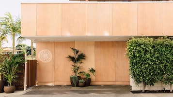 A modern building with a wooden facade, potted plants, and a logo on the wall.