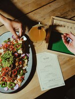 Un tavolo di legno con un piatto di nachos, una bevanda e un menu.