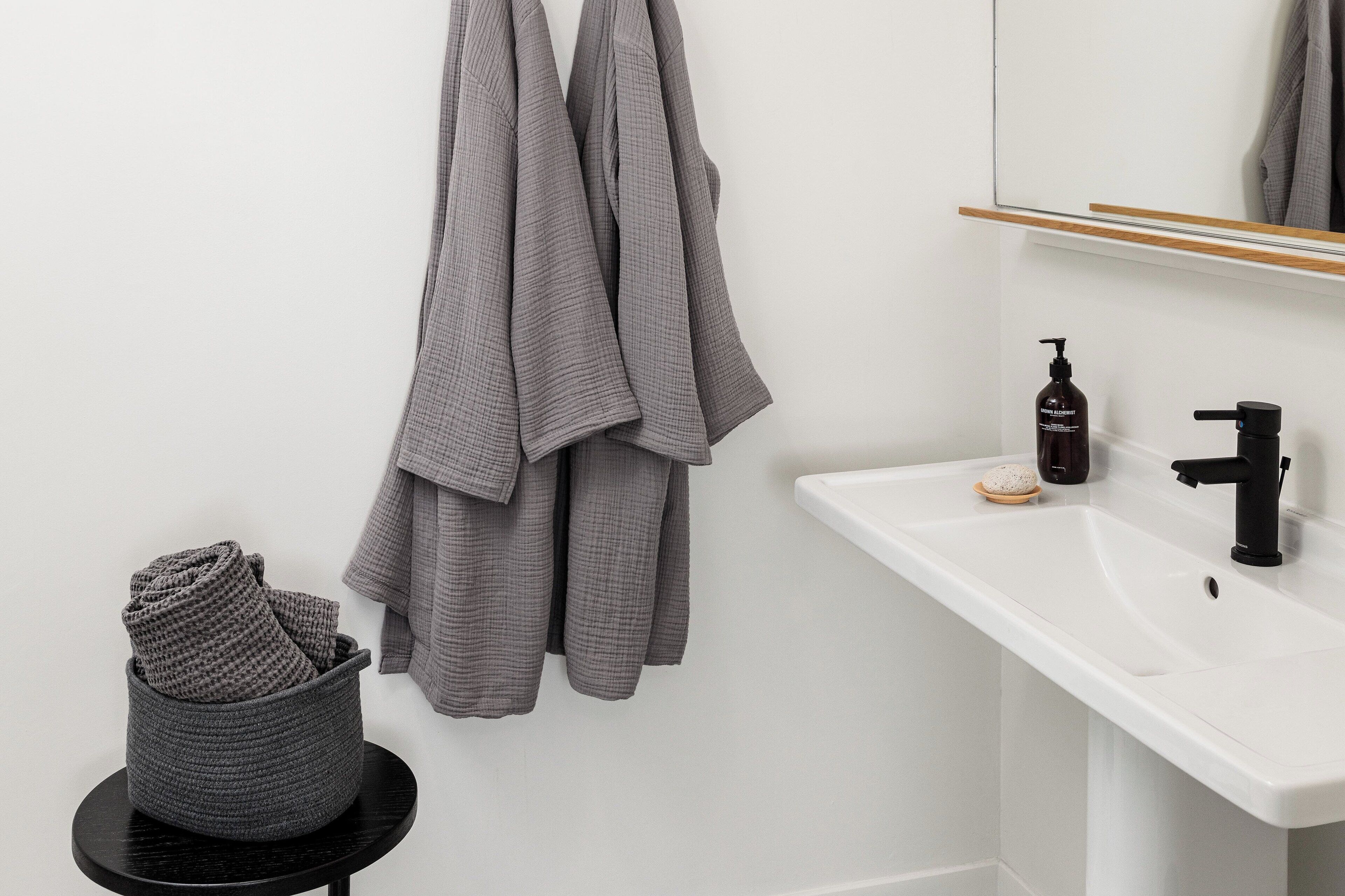 A bathroom with a white sink, black faucet, and a bottle of hand soap.