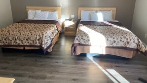 Ett hotellrum med två sängar, trägavlar och ett nattduksbord mellan dem.