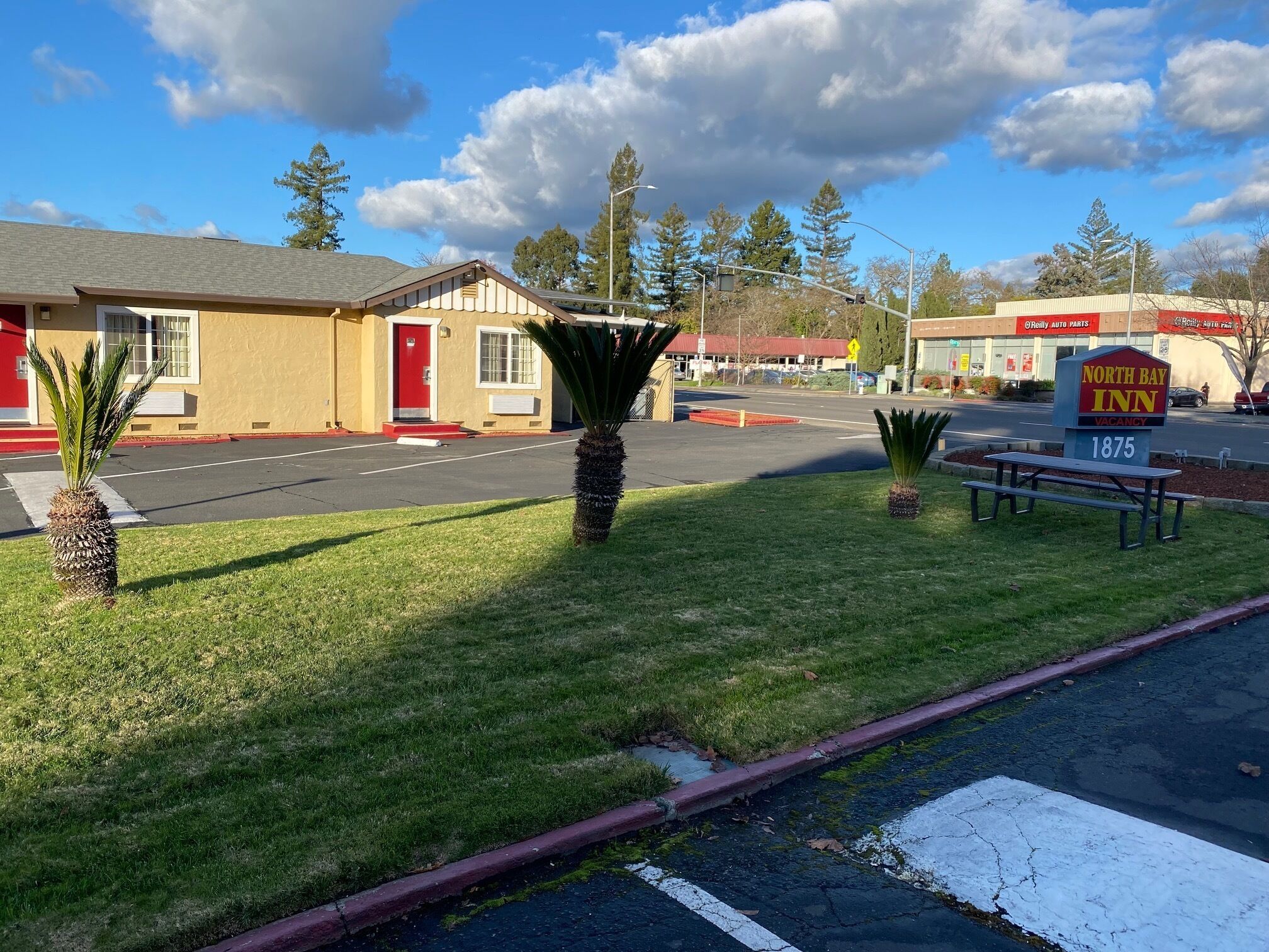 Um motel com porta vermelha, estacionamento e placa indicando North Bay Inn.