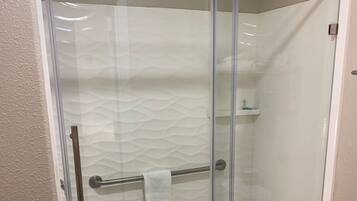 A glass-enclosed shower with a towel rack and a toilet.