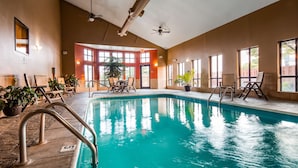 An indoor swimming pool with clear blue water, surrounded by lounge chairs and potted plants. - Best Western Plus Country Inn & Suites (Dodge City)