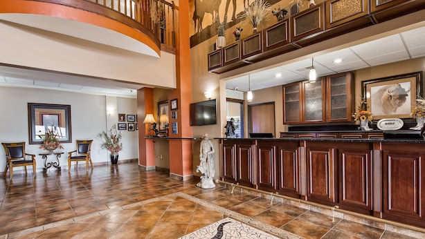 A spacious lobby with a high ceiling, a grand staircase, and a reception area with a counter and decorative items. - Best Western Plus Country Inn & Suites (Dodge City)