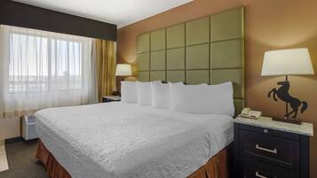 A hotel room with a large bed, a nightstand with a lamp, and a headboard.