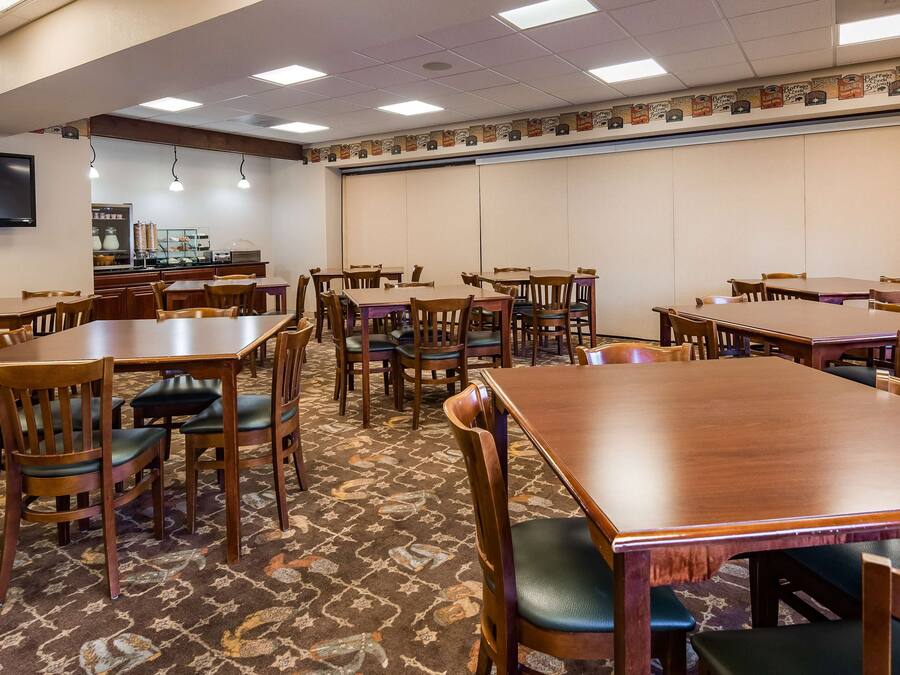 A conference room with multiple tables and chairs, a flat-screen TV mounted on the wall, and a patterned carpet.