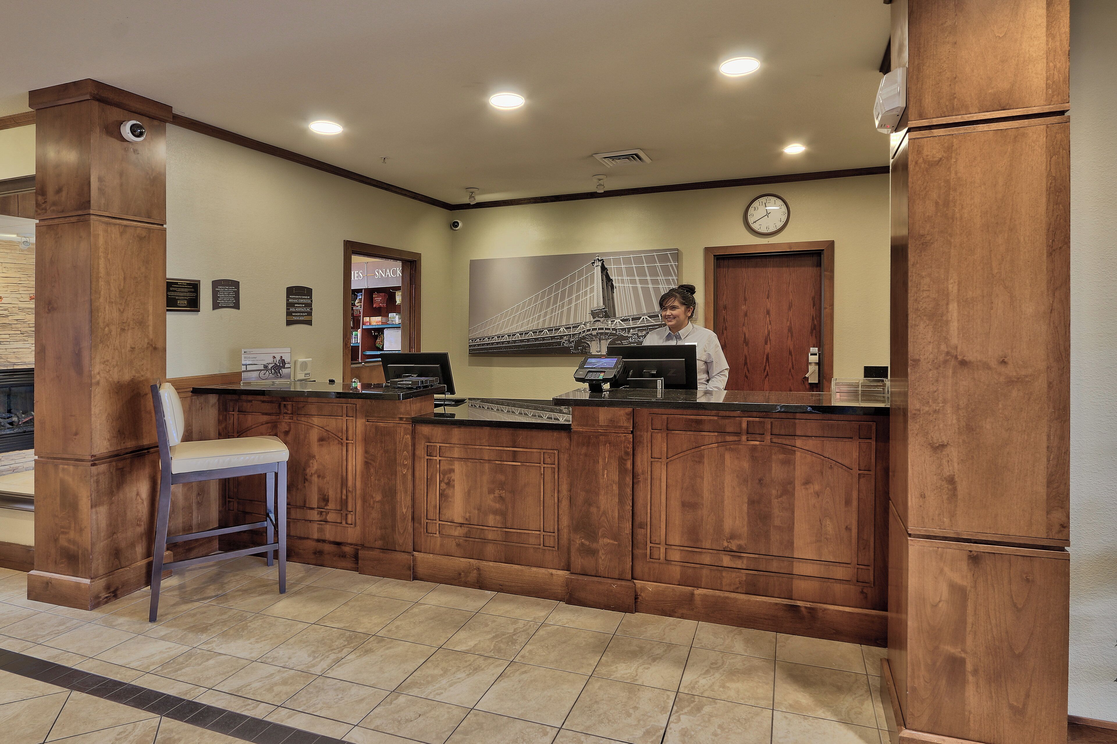 A reception desk with a wooden finish, a clock, and a wall-mounted sign.