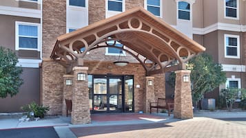 A building entrance with a stone facade, a covered porch, and a bench.