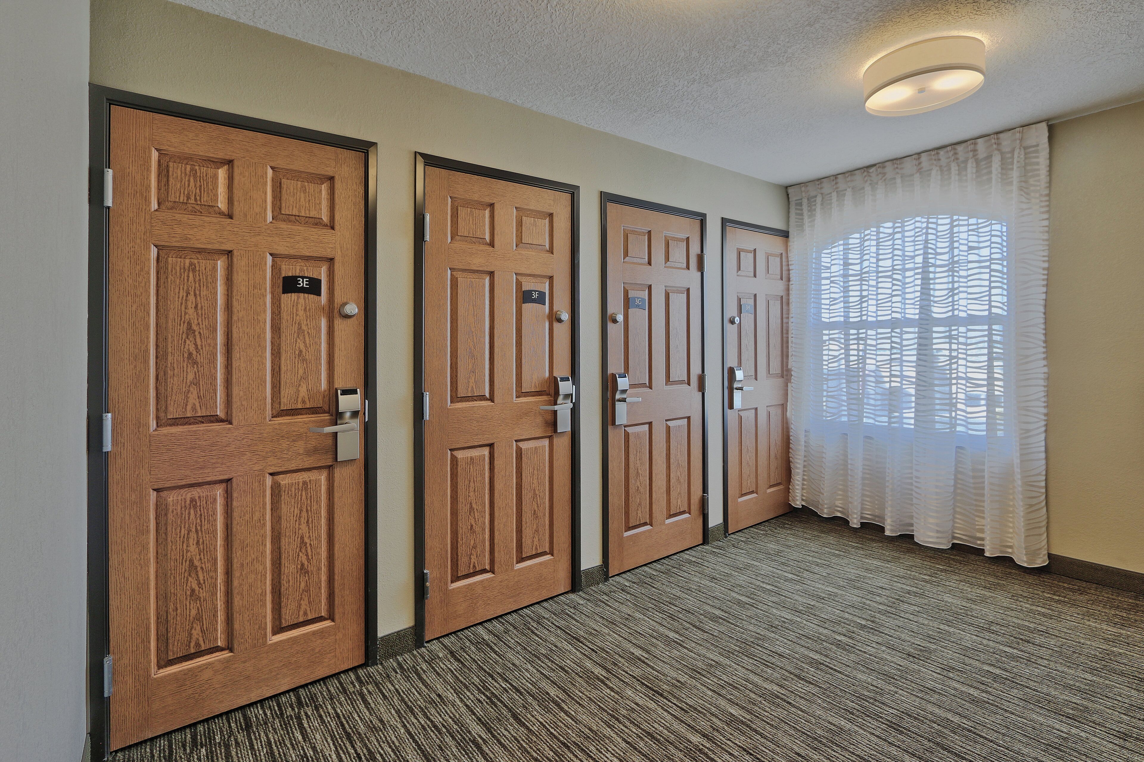 A hallway with three wooden doors, each with a number plate, leading to individual rooms.