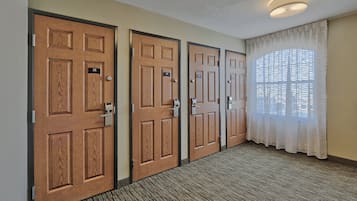 A hallway with three wooden doors, each with a number plate, leading to individual rooms.
