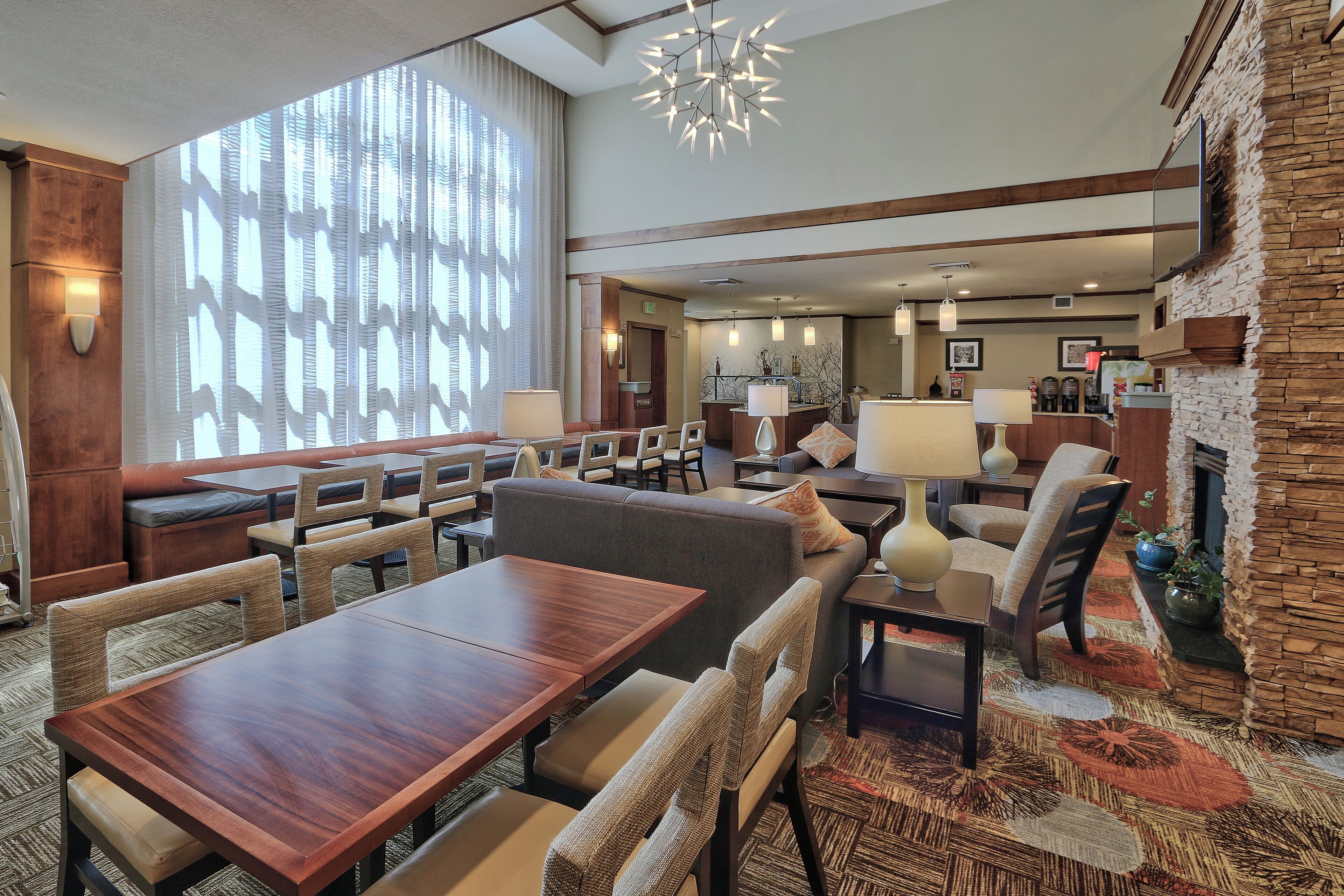 A hotel lobby with a dining area, seating arrangements, and a fireplace.