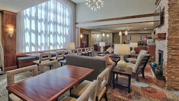 A hotel lobby with a dining area, seating arrangements, and a fireplace.