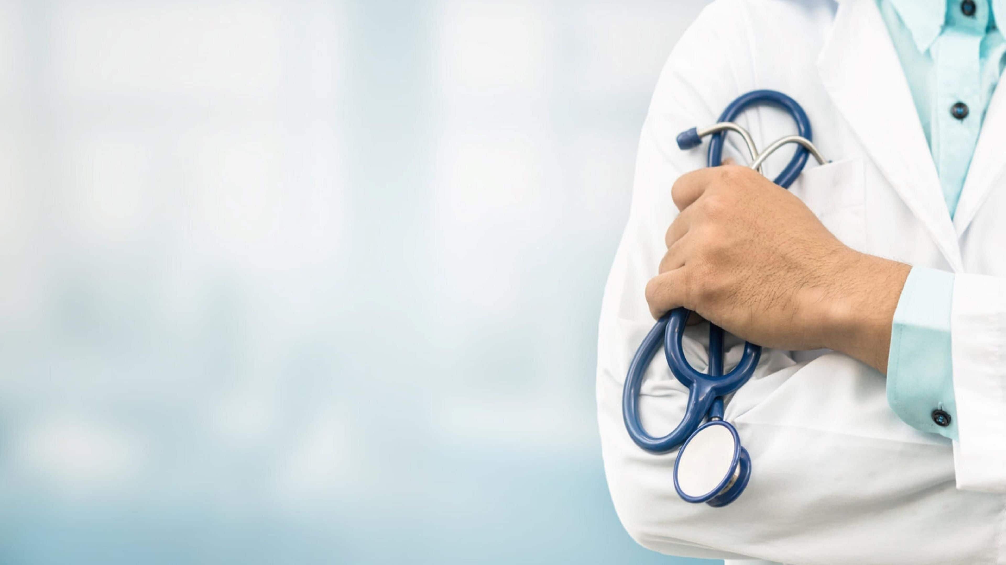 A person in a white lab coat holding a stethoscope.