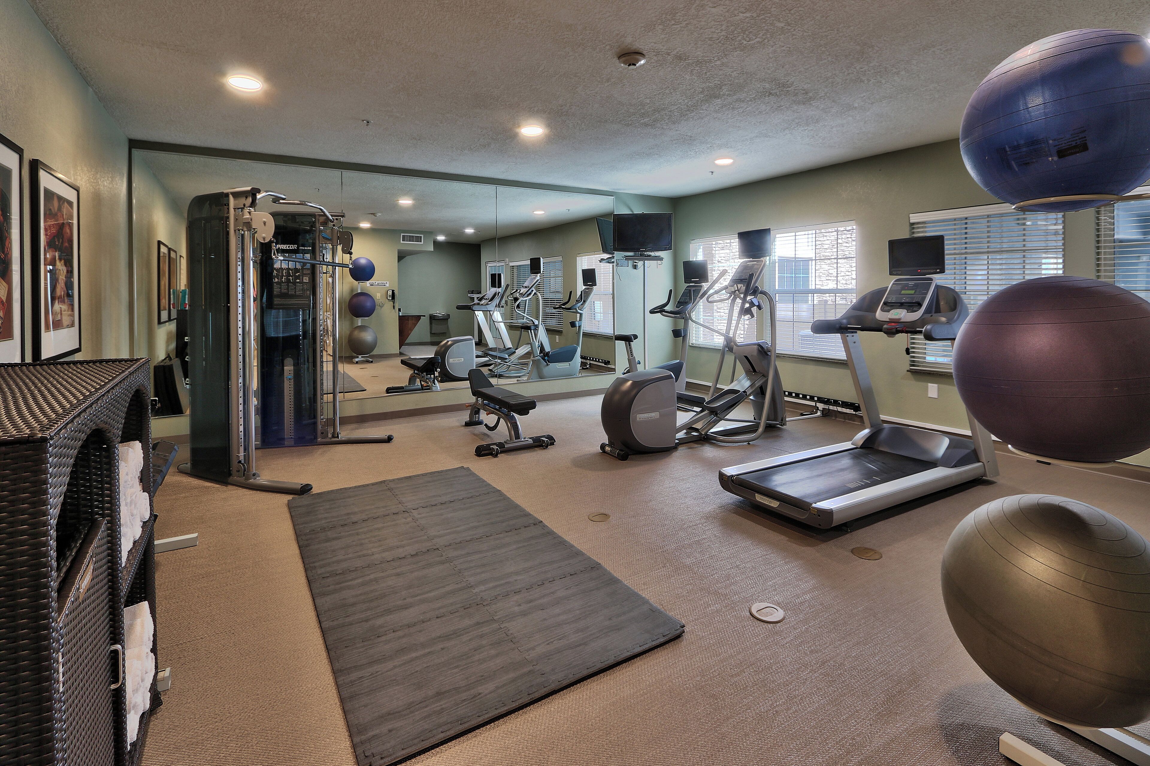 Ein Fitnessstudio mit unterschiedlichen Trainingsgeräten, darunter Laufbänder, Ergometer und Kurzhanteln.