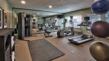 Ein Fitnessstudio mit unterschiedlichen Trainingsgeräten, darunter Laufbänder, Ergometer und Kurzhanteln.