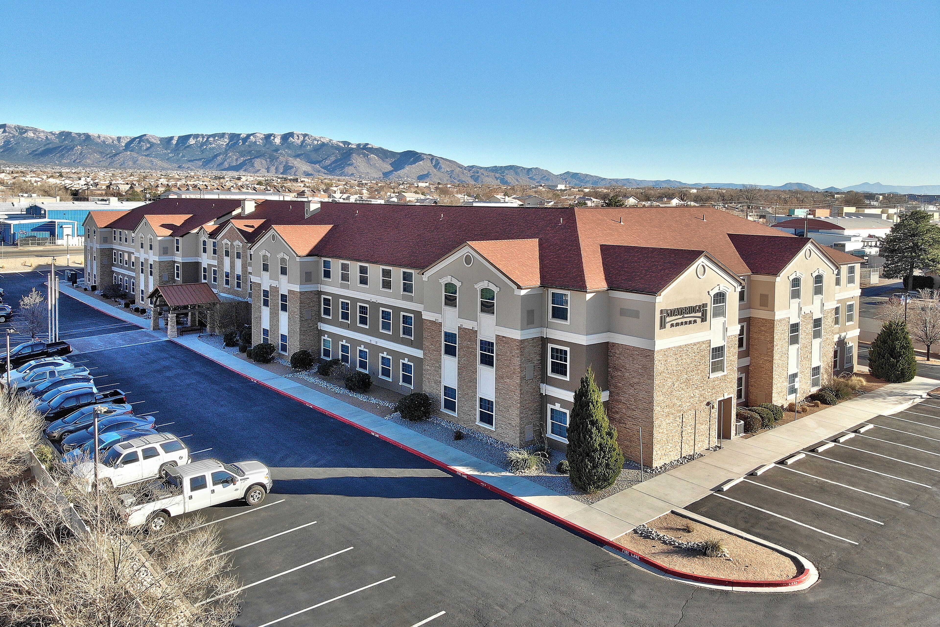 A multi-story hotel with a parking lot and a view of mountains in the background.