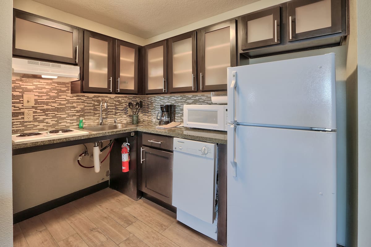 A kitchen with dark wooden cabinets, a white refrigerator, a microwave, and a dishwasher.