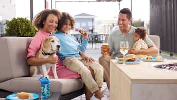 A family dining outdoors with a dog, a table with food and drinks, and a patio setting.