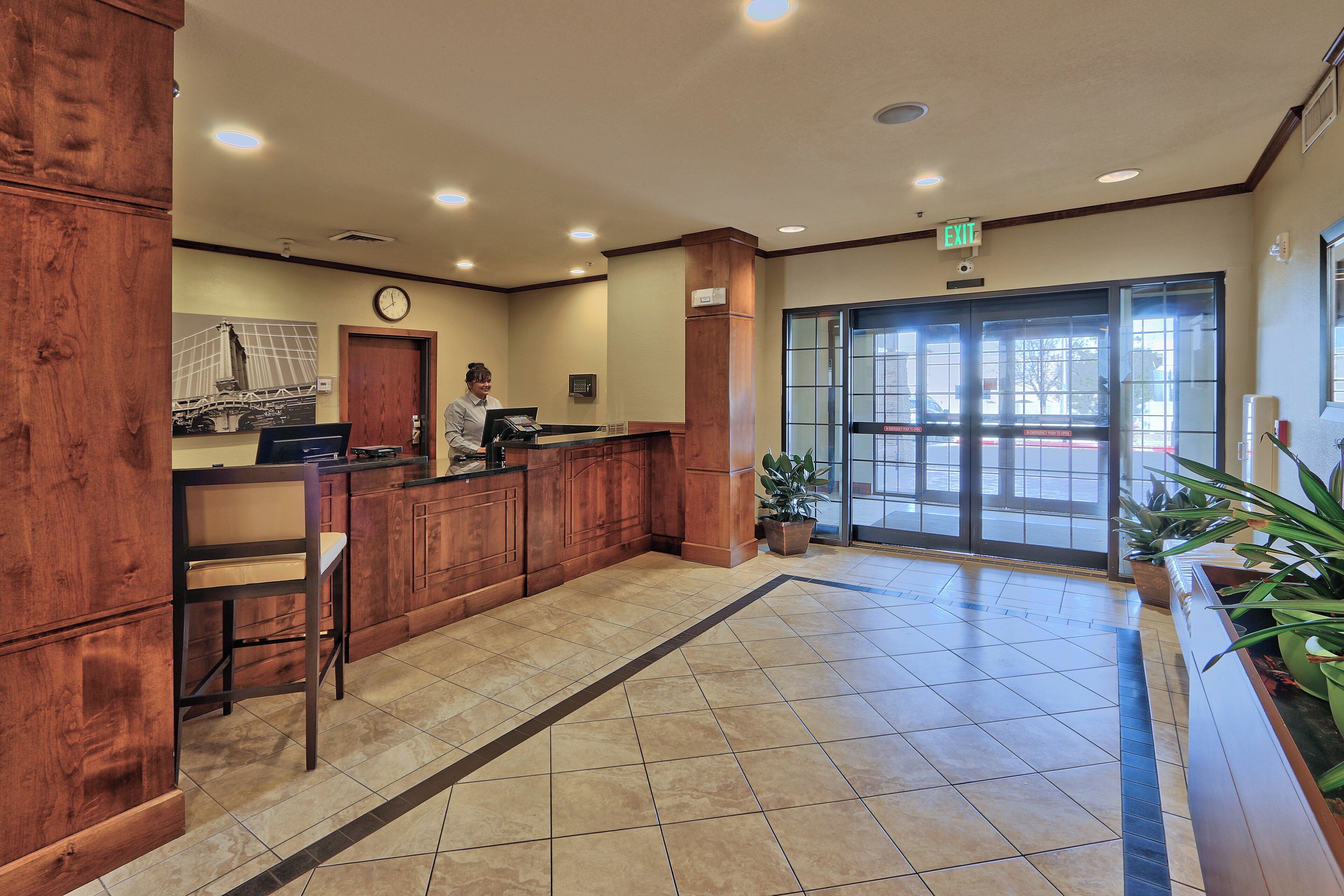 A reception area with a wooden reception desk, a clock, and a large glass door leading outside.