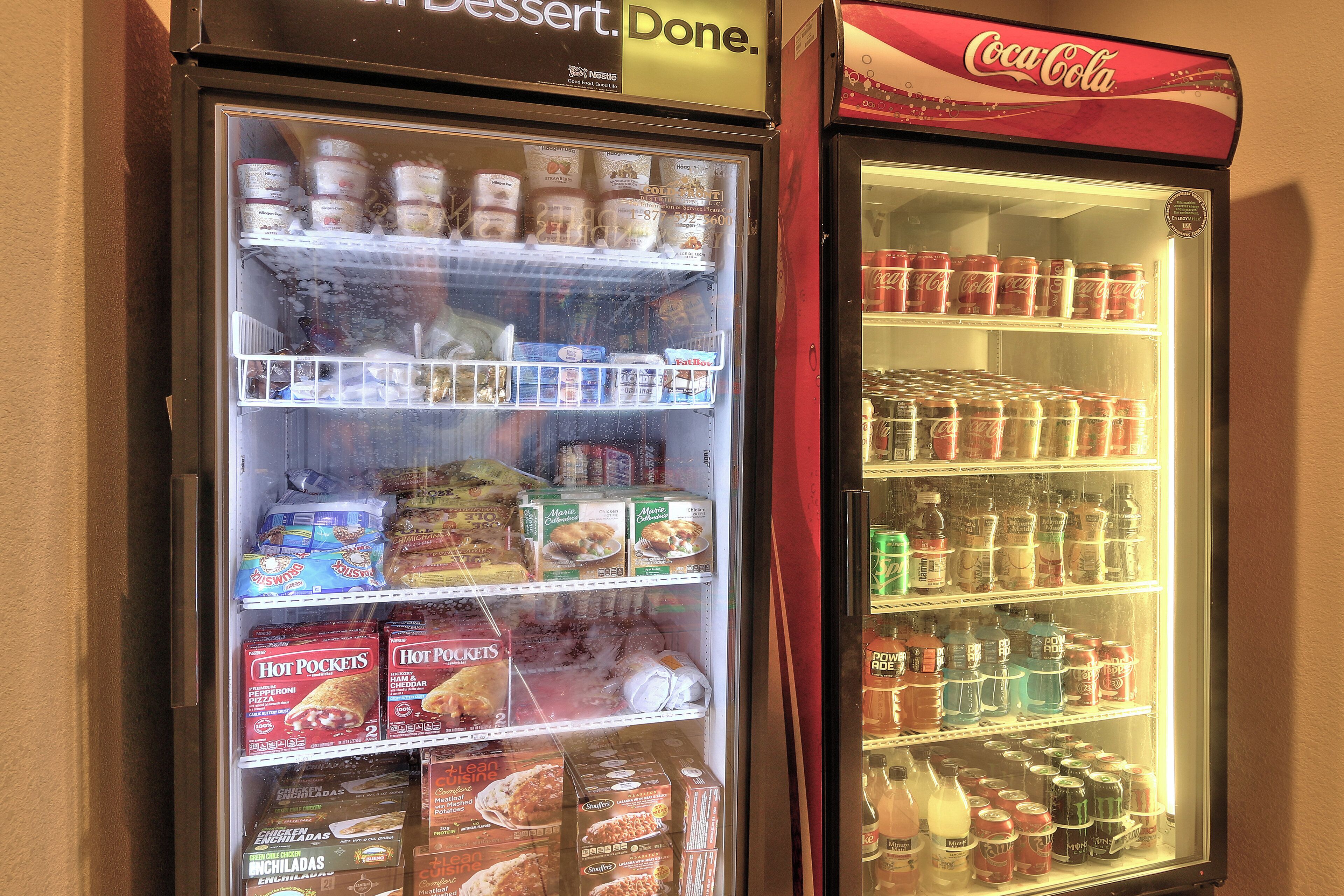 Una máquina expendedora con diferentes productos alimenticios y un refrigerador de Coca-Cola lleno de bebidas.