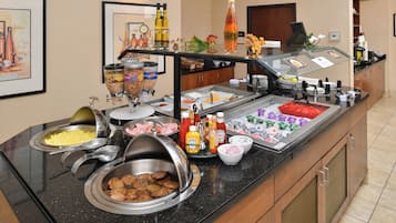 A buffet setup with various food items and condiments.