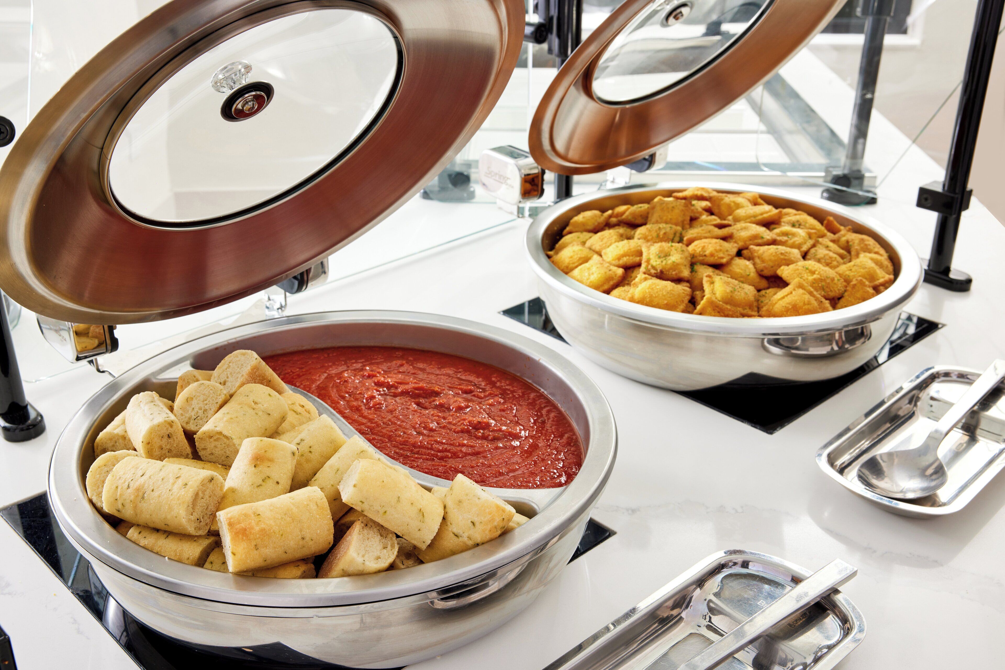 A buffet setup with various food items including dips and rolls.