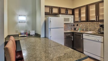 A kitchen with granite countertops, stainless steel appliances, and dark wooden cabinets.