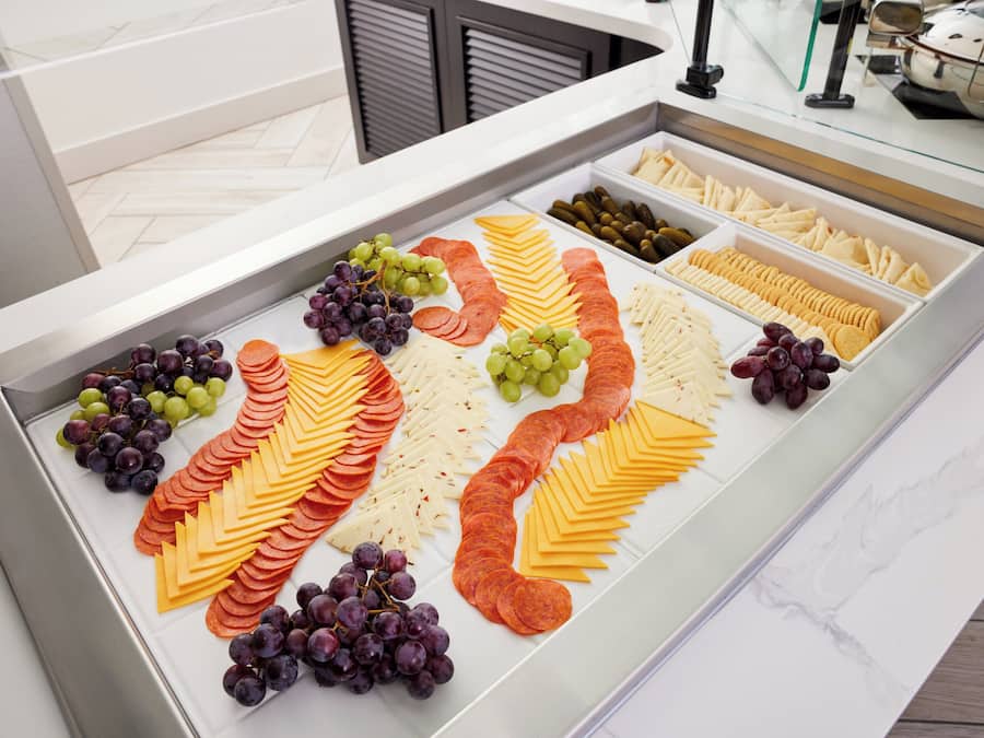 A buffet spread with various cheeses, sliced meats, and grapes.