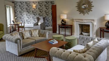 Una sala de estar con papel tapiz estampado, una chimenea y dos sofás.
