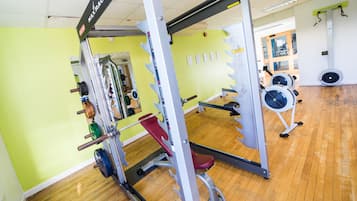 A gym with a variety of equipment including a squat rack, bench press, and free weights.