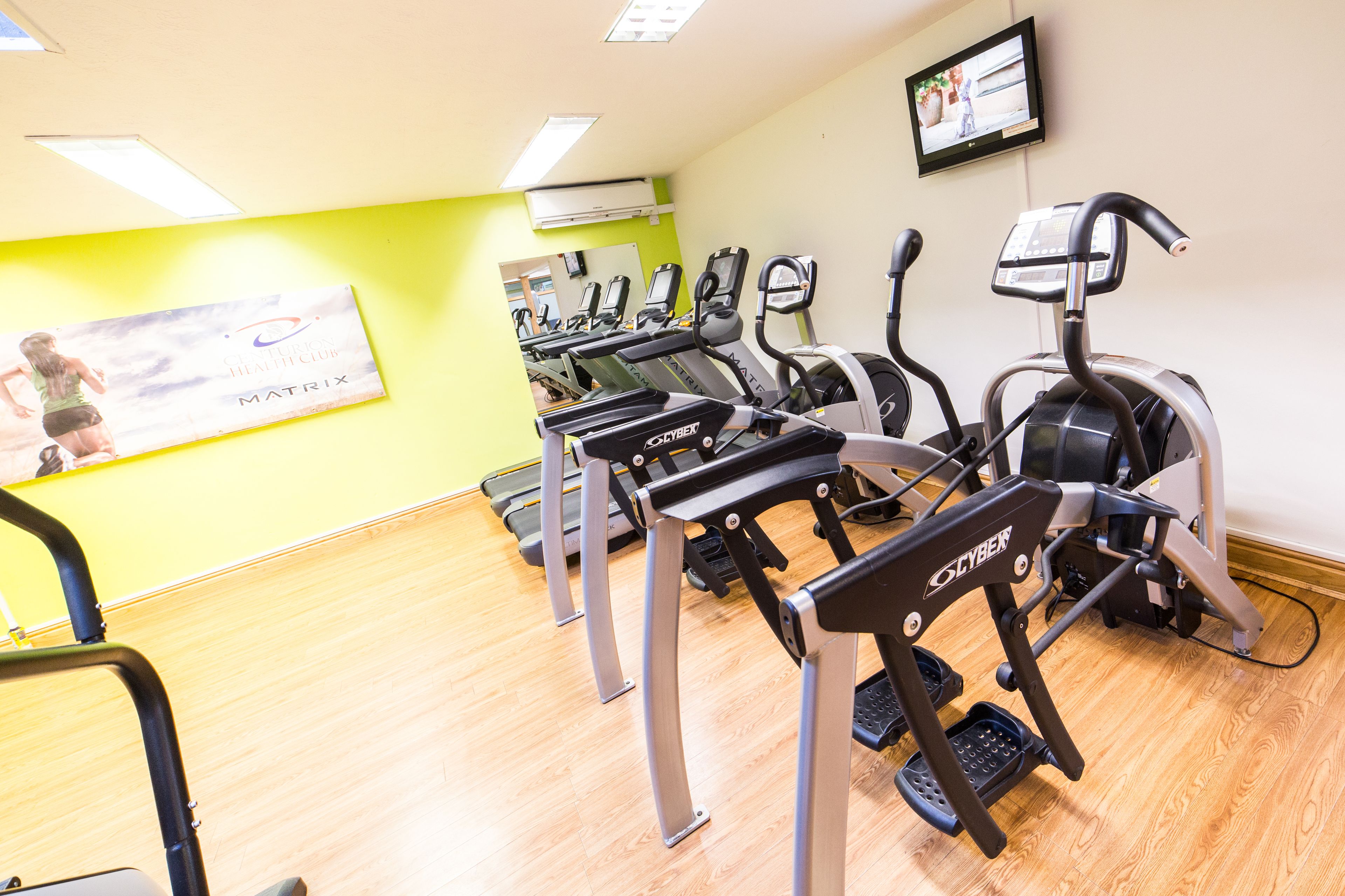 A gym with multiple treadmills, a mirror, and a poster on the wall.