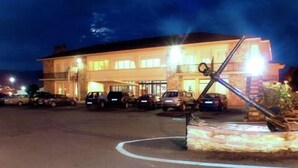 Un hotel con un estacionamiento amplio y una escultura destacada de un ancla al frente.