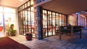 Una mesa de billar en una sala con paredes de piedra y ventanas amplias.