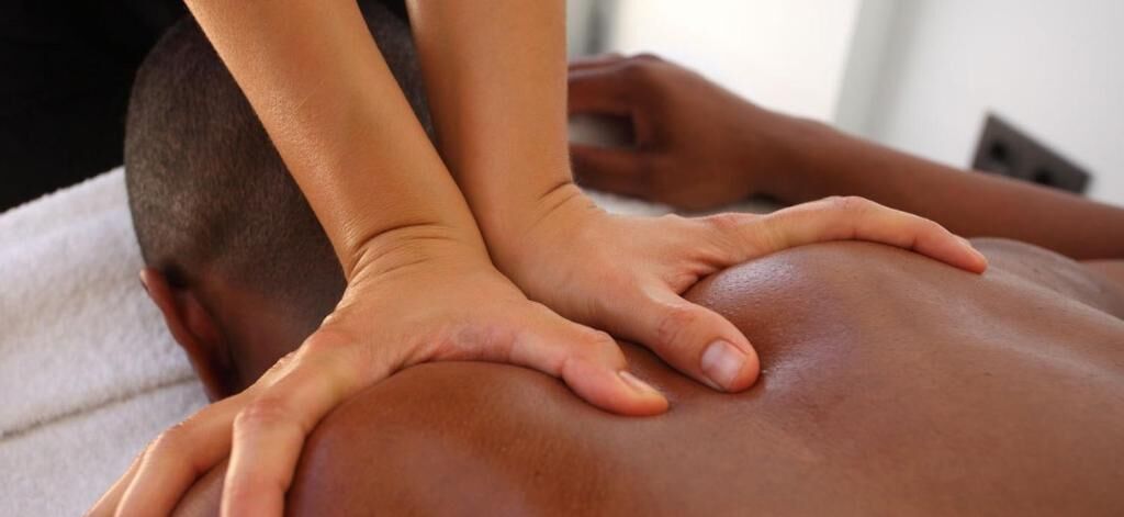 Nahaufnahme von Händen, die eine Rückenmassage geben.