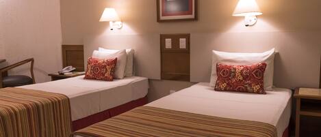 Two single beds with striped bedding, bedside lamps, and a framed artwork on the wall.