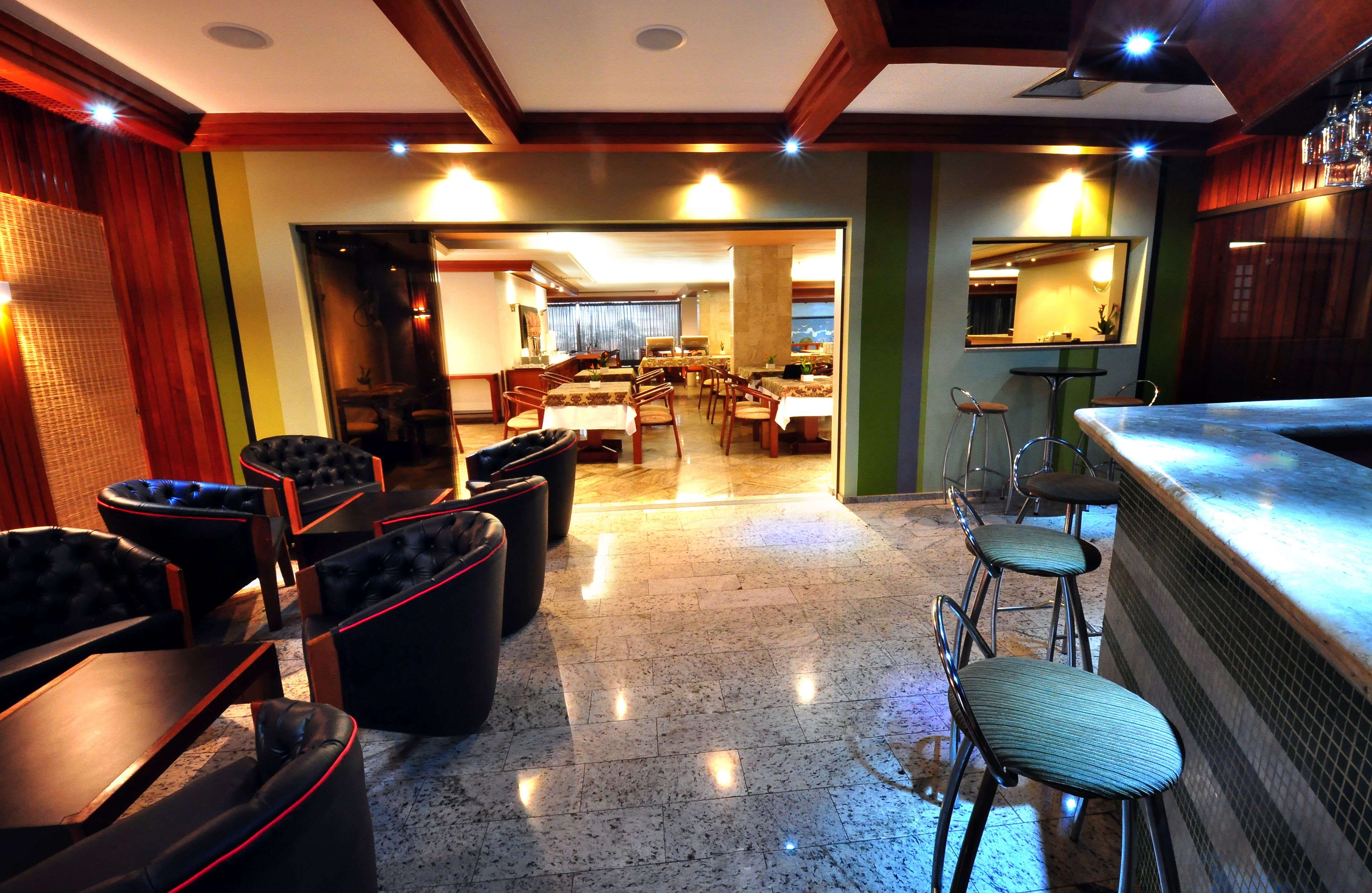 Un restaurante con área de bar, varias mesas y sillas.