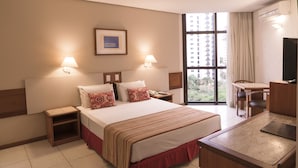 Une chambre d’hôtel comprenant un lit, des tables de chevet, un bureau, une chaise et un téléviseur.