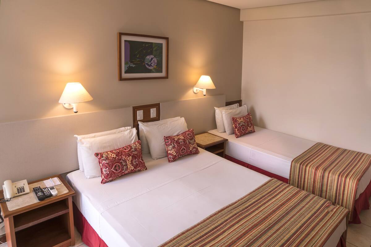 Habitación de hotel con dos camas, cada una con almohada y mesita de noche con lámpara y teléfono.
