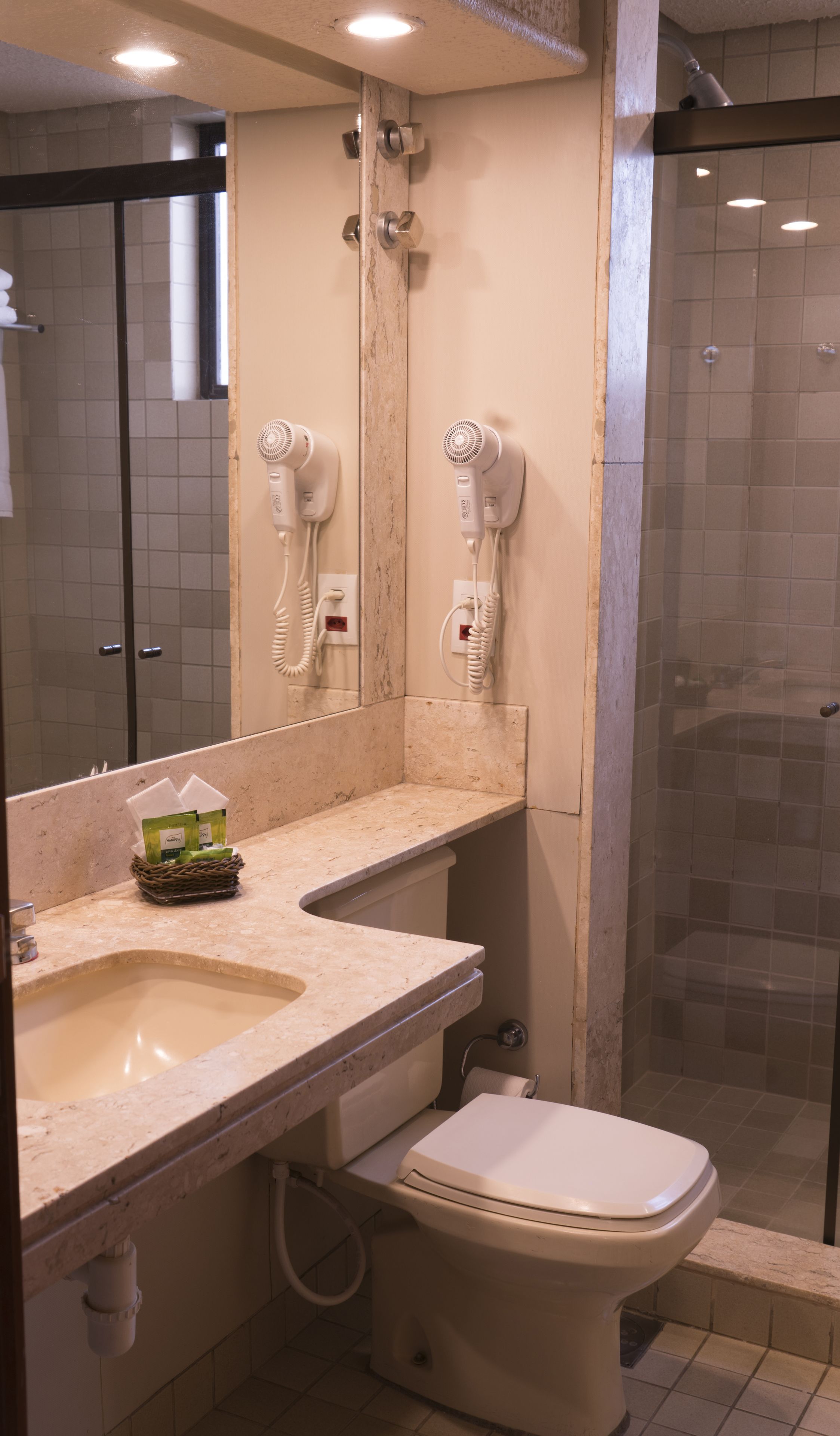 Une salle de bain équipée d’un lavabo, d’un miroir, d’un sèche-cheveux et de toilettes.